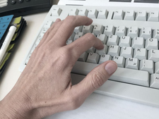 Eine Hand schreibt auf einer Computertastatur