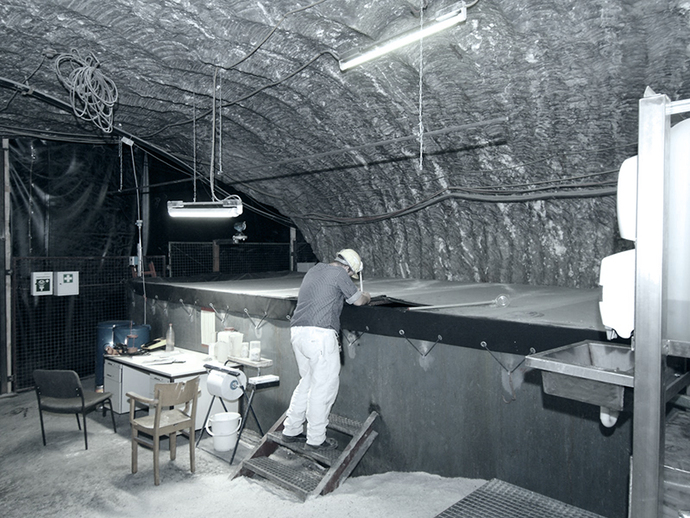 Ein Bergmann entnimmt eine Probe aus einem Behälter für Zutrittswässer. Ein Bergmann entnimmt eine Probe aus einem Behälter für Zutrittswässer.