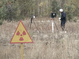 Messung der Radioaktivität in der Sperrzone rund um das havarierte Kernkraftwerk Tschernobyl mit zwei verschiedenen Typen von Gammaspektrometern – im Vordergrund warnt ein Schild vor erhöhter Radioaktivität (Bild anzeigen)