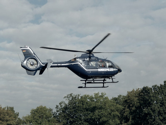 A helicopter flies low above a piece of woodlands (show image)