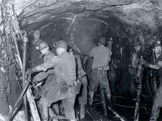 Bergarbeiter unter Tage beim Bohren im Wasser stehend