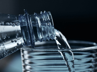 Wasser fließt aus einer Flasche in ein Glas Wasser fließt aus einer Flasche in ein Glas