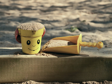 ein Sandkasten im Schatten mit Spielzeugeimer und Schaufel