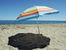 Ein Sonnenschirm am Strand wirft Schatten