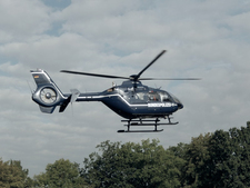 A helicopter flies low above a piece of woodlands